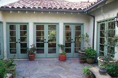 a patio with potted plants on the side and glass doors to another room in the back