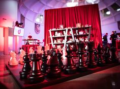 a giant chess set up in front of a red curtain with other pieces on it