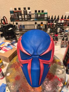 a blue and red mask sitting on top of a table next to other items in the background