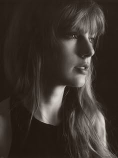 a black and white photo of a woman with long hair looking off to the side