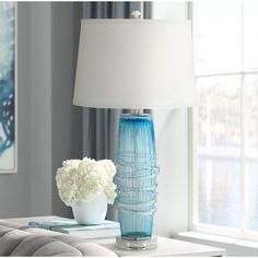 a blue vase with white flowers sitting on a table next to a lamp