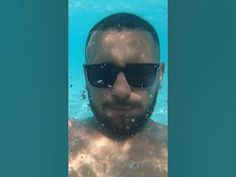 a man wearing sunglasses is swimming in the water