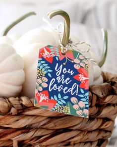 a basket filled with lots of white pumpkins and some kind of tag that says you are loved