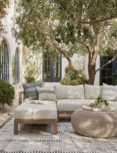 an outdoor living room with white furniture and trees