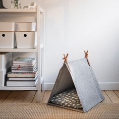 a teepee tent sitting on top of a wooden floor next to a book shelf