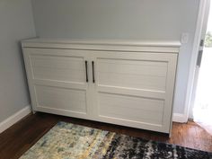 a large white cabinet sitting in the corner of a room next to a door and rug