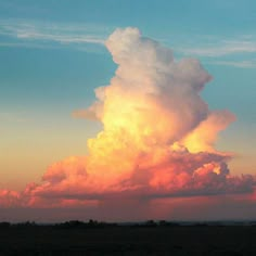 a large cloud is in the sky at sunset