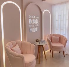 two pink chairs and a small table in a room with arched windows on the wall