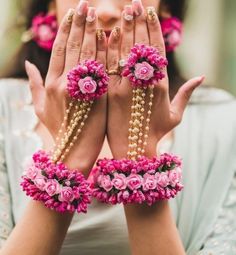 a woman is holding her hands together with flowers on them and beads around her wrists