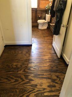 a wooden floor in a bathroom next to a white door