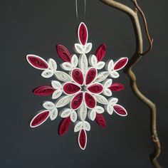 a red and white ornament hanging from a tree branch on a dark background