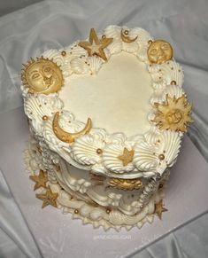 a white cake with gold stars and moon decorations on it's sides is sitting on a table