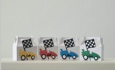 small paper bags with cars and checkered flags are lined up on a shelf in front of a white wall