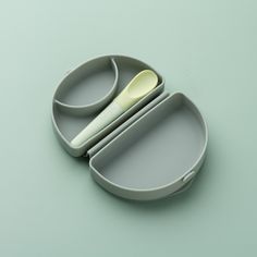 a set of three bowls with spoons in them on a green surface, one is empty and the other has two compartments