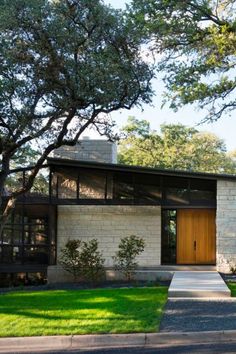 a modern house with grass and trees in the front yard