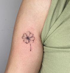 a small four leaf clover tattoo on the left upper half of the arm and shoulder