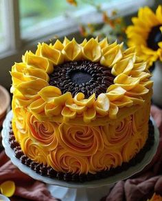 a sunflower cake with chocolate frosting is on a table next to some flowers