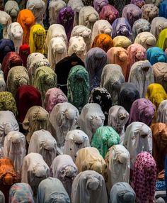 a large group of people standing in front of each other wearing different colored headscarves