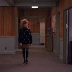 a woman walking down a hallway in an office building