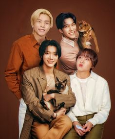 four people are posing with one holding a cat