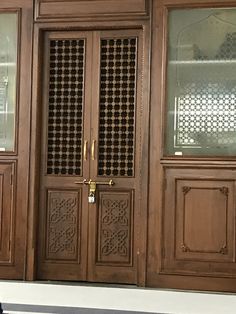 a cat sitting on the ground in front of a wooden door with decorative carvings and glass panels