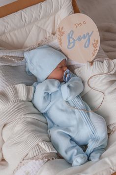 a baby is sleeping in a crib with a wooden sign that says i'm a boy