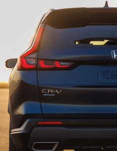 the rear end of a blue honda cr - v parked on a road in the sun