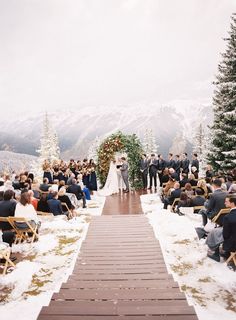 a wedding ceremony in the mountains with snow on the ground and people sitting at chairs