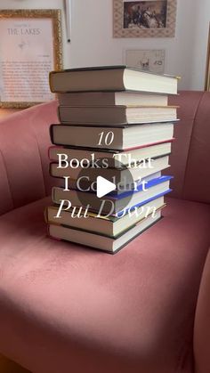 a stack of books sitting on top of a pink couch