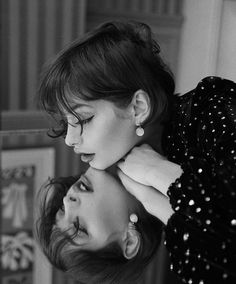 black and white photograph of two women touching each other's heads with their hands