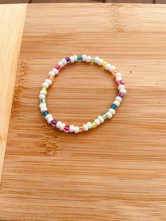 a bracelet with multicolored beads sitting on top of a wooden table