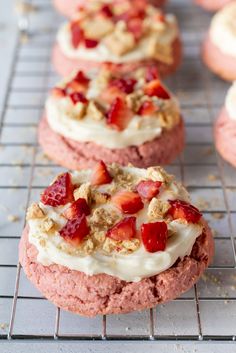 strawberry shortcakes with cream cheese frosting and strawberries on top are cooling on a wire rack