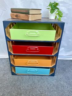 four drawers stacked on top of each other with books and a plant in the background