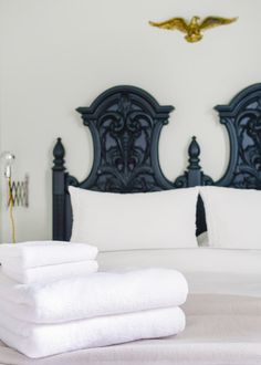 folded towels on top of a bed in a bedroom with white walls and black headboard