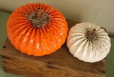 two orange and white pumpkins sitting on top of a wooden box