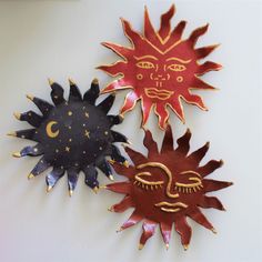 three metal sun and moon wall hangings on a white surface, one with gold accents