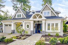 a gray house with white trim and windows on the front door is surrounded by greenery