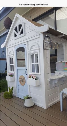 a white doll house sitting on top of a wooden floor next to a table and chairs