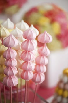 there are many pink and white candies on the stick in the cupcake display