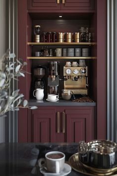 a coffee maker is sitting on the counter in front of some cups and saucers