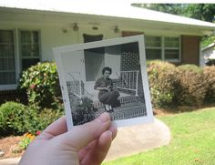 a person holding up an old photo in front of a house