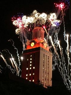 fireworks are lit up in the night sky above a clock tower with a clock on it