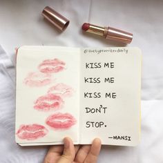 a hand holding an open notebook with lipstick on it and the words kiss me, kiss me, kiss me don't stop