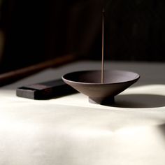 a wooden bowl sitting on top of a table next to a black object with sticks sticking out of it