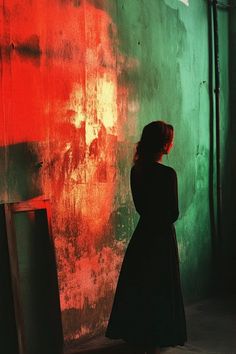 a woman standing in front of a wall with red and green paint on it's walls