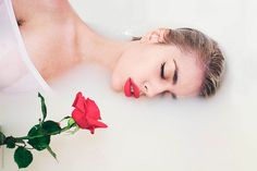 a woman laying in a bathtub with a red rose next to her face by jodi jones for stockstation photography