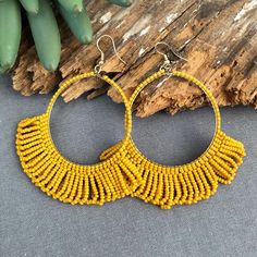 a pair of yellow beaded hoop earrings sitting on top of a piece of wood