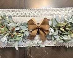 a close up of a bow on a door handle with leaves and berries around it