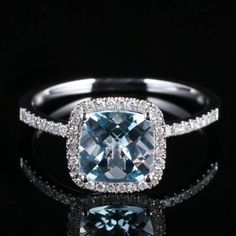 a ring with an aqua blue diamond surrounded by white diamonds on a black reflective surface