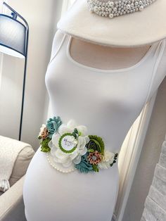 a pregnant woman wearing a white dress and flower belt